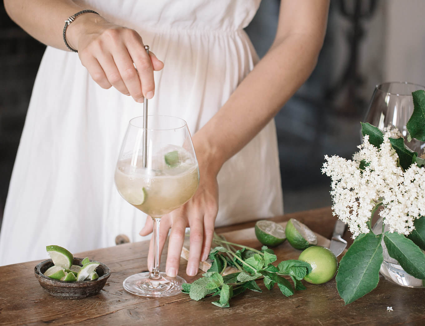 woman mixing tea, lime and mint in a cocktail glass
