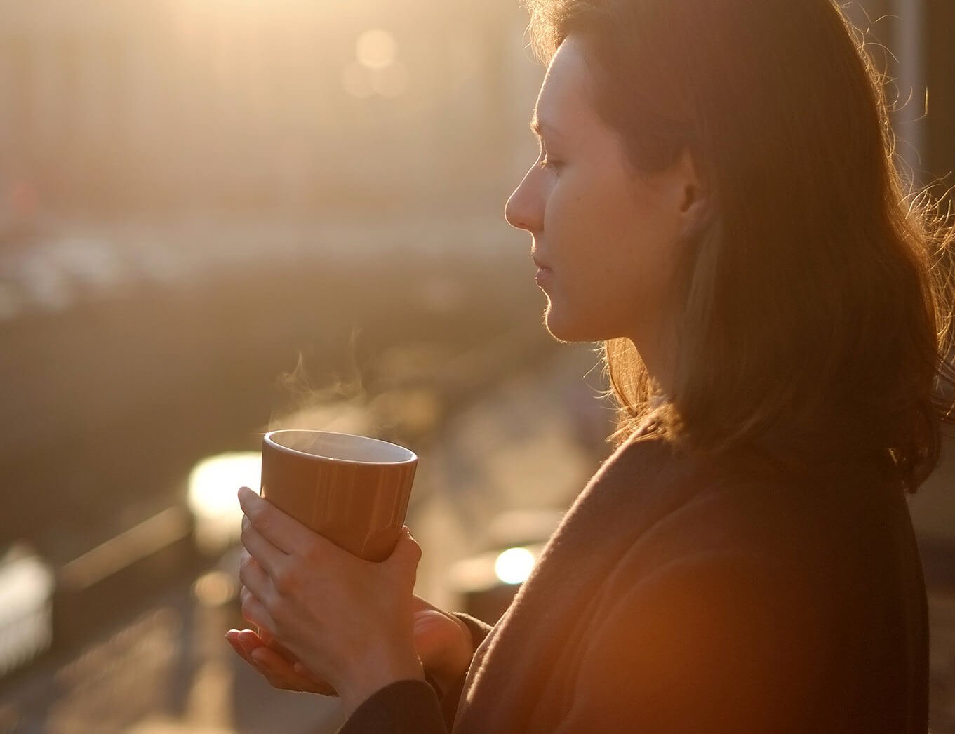 woman holding a cup of tea with steam coming out of it