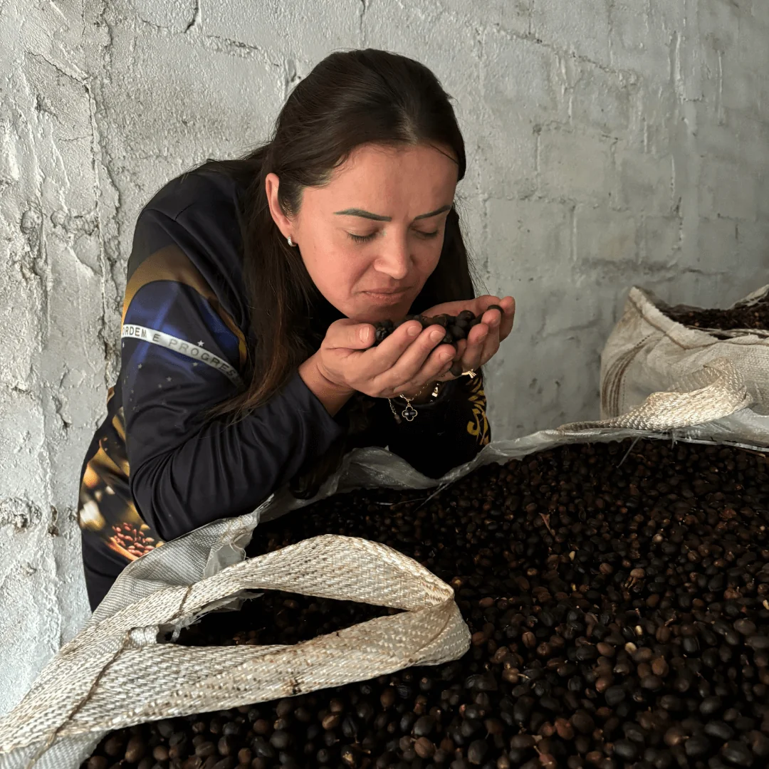 Female farmer smelling coffee beans on Brazil origin trip