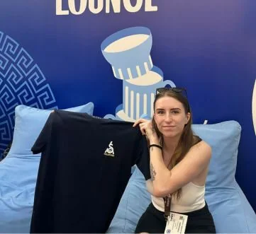 girl sitting on a sofa holding up a t shirt
